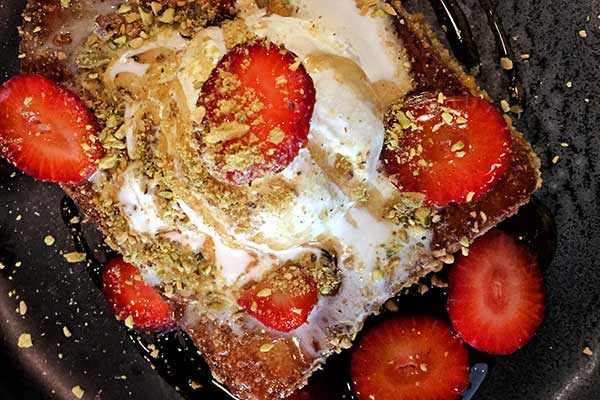 Toast with icecream sprinkled with crushed nuts and strawberries