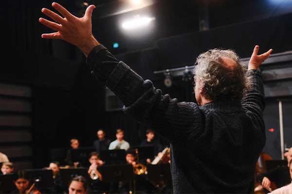 conductor with hands up in front of orchestra