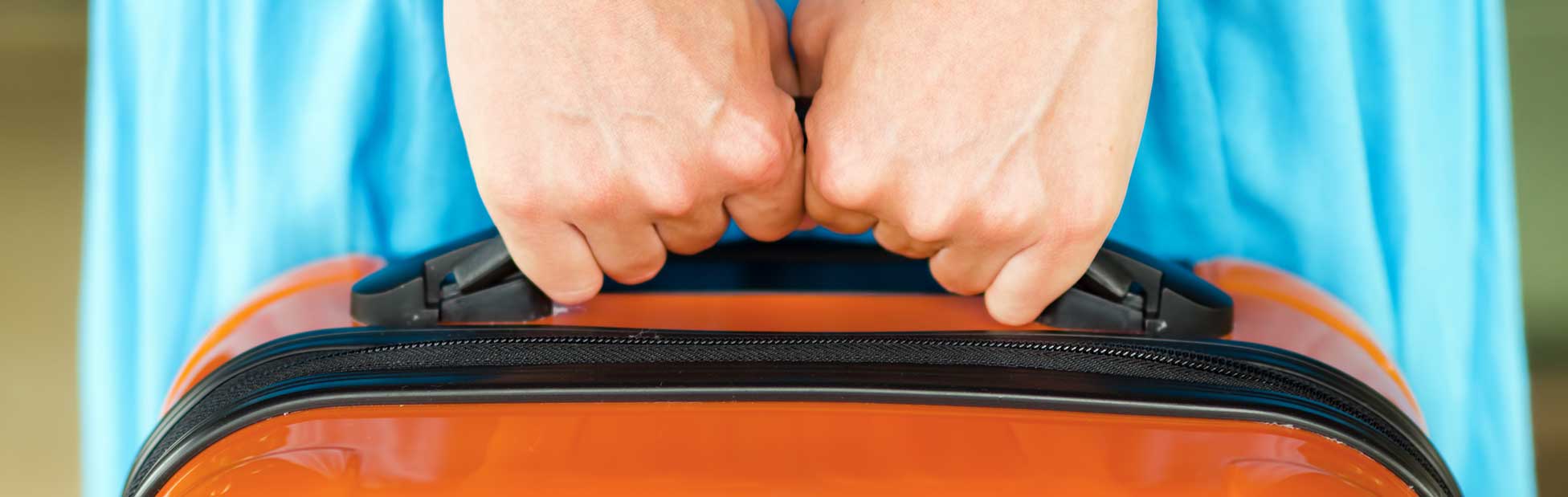 Hands holding bright orange suitcase