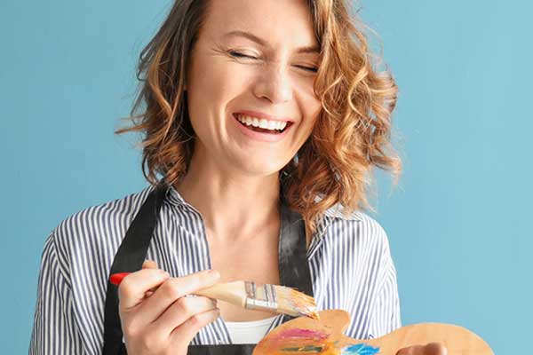 woman with paint brush laughing