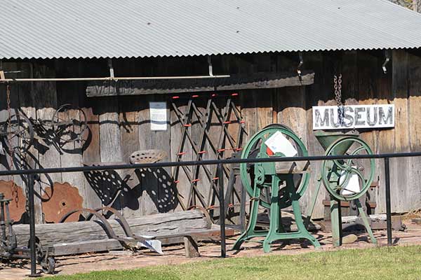An assortment of old farming tools outside a shed