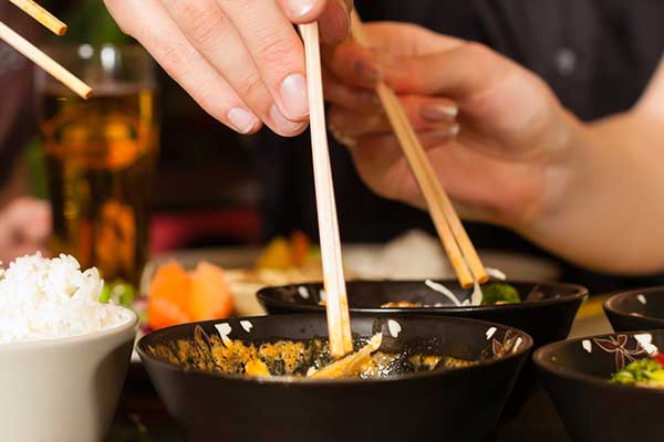 Hands with chop sticks grabbing chinese food from bowls