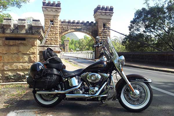 Harley Davidson motorbike parked in front of an old stone bridge